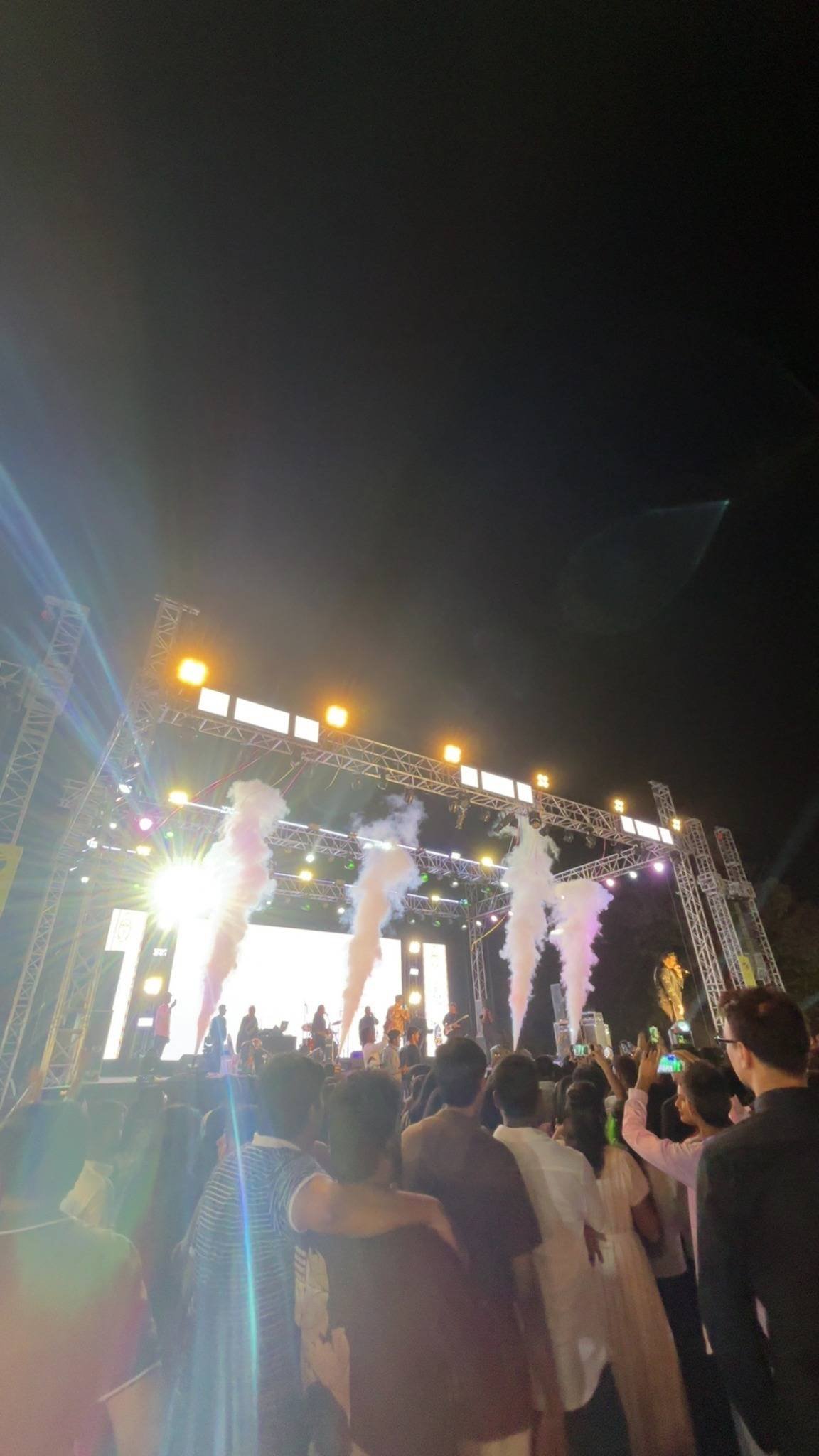 CO₂ jets fire in front of a glowing LED wall while the crowd watches.
