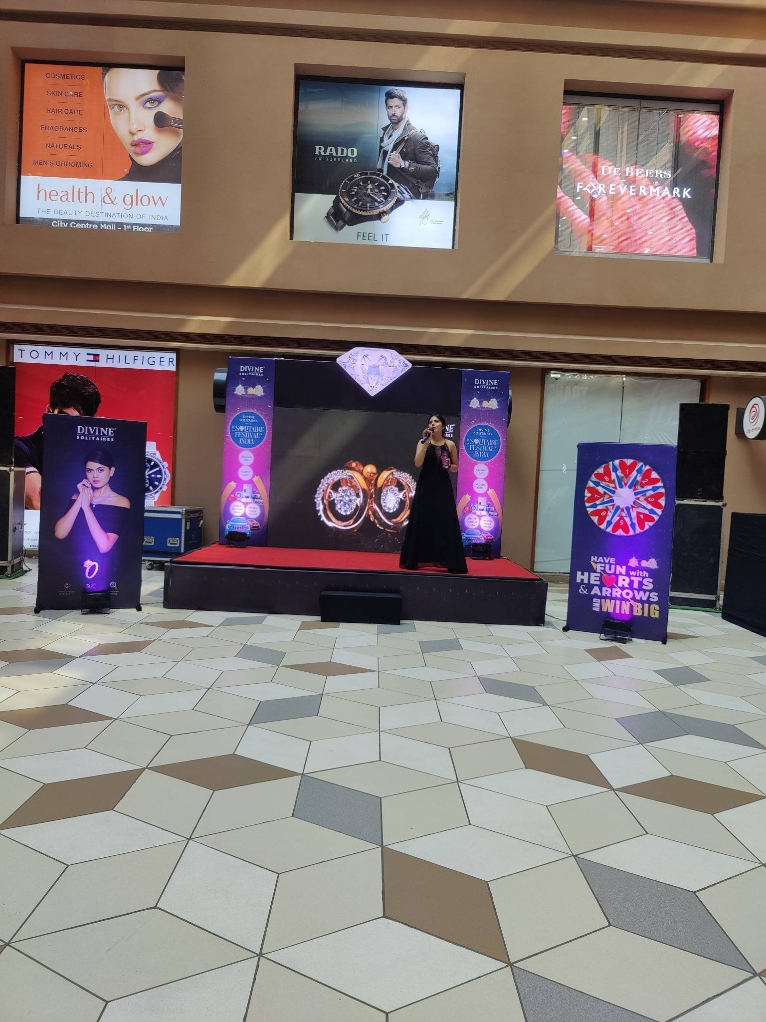 Brand activity setup with a stage, standees and LED screens in a mall atrium.