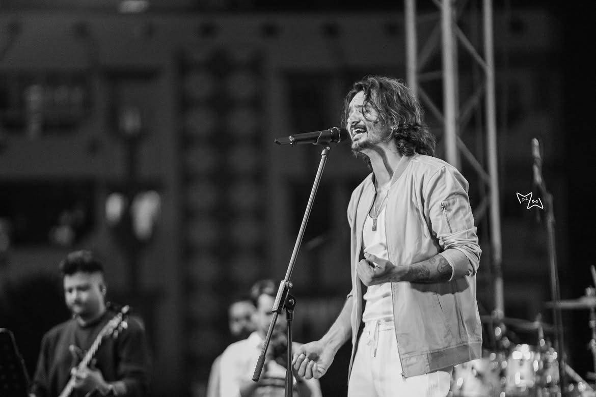 Black-and-white photograph of Gajendra Verma singing at the microphone with his band on stage.