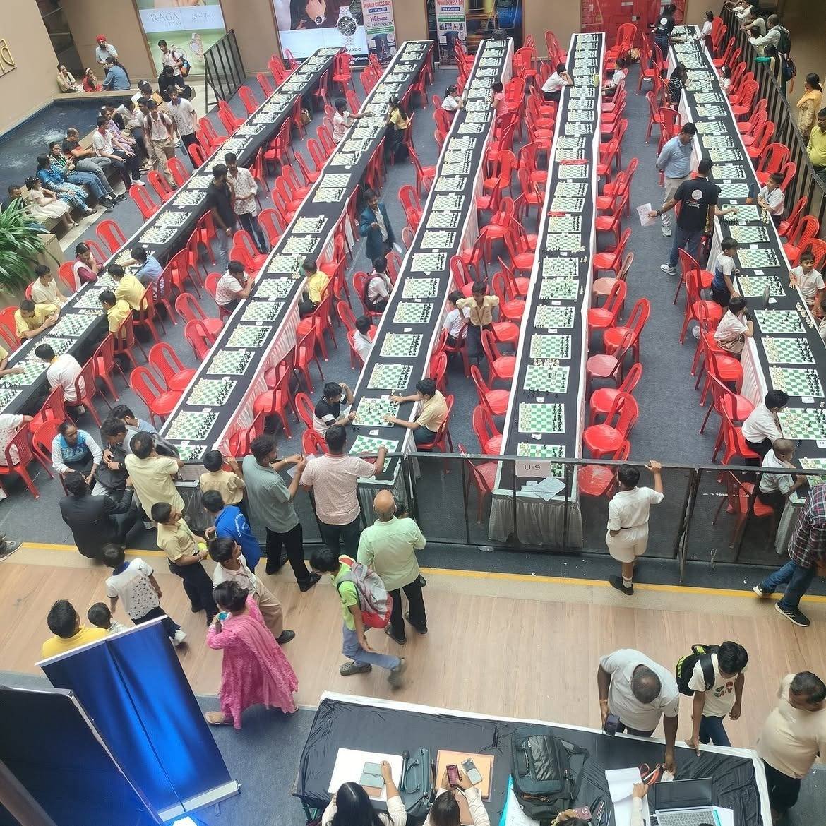 Overhead view of long rows of chess tables at an inter-school chess event in a mall atrium.